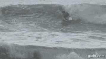 a surfer is riding a wave in the ocean with the website gickr.com visible in the background