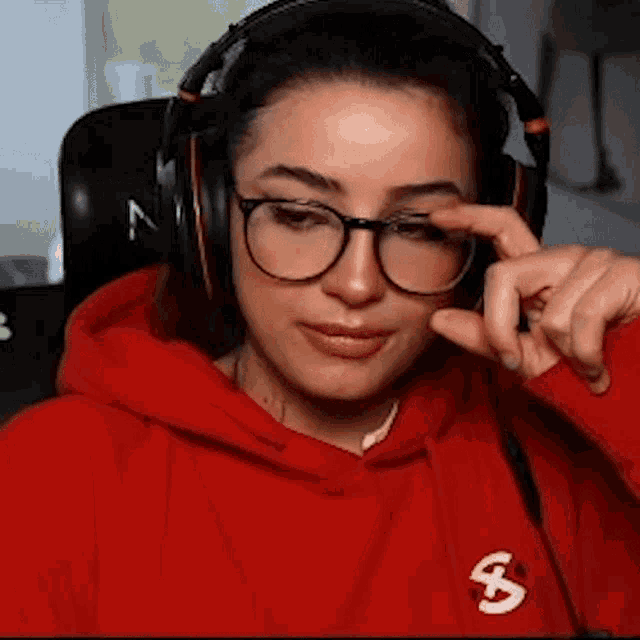 a woman wearing glasses and headphones is sitting in a chair and making a funny face .