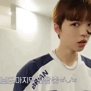 a young man wearing a necklace and a t-shirt is standing in a room .