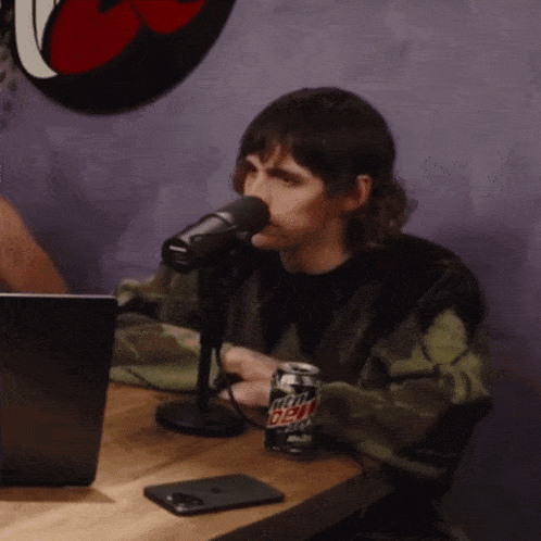 a man sitting at a table with a can of mtn dew