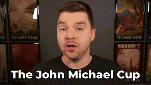 a man in a black shirt stands in front of a wall with pictures and the words " the john michael cup " above him