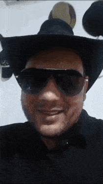 a man wearing a hat and sunglasses is smiling