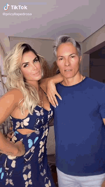 a woman in a blue dress and a man in a blue shirt are standing next to each other .