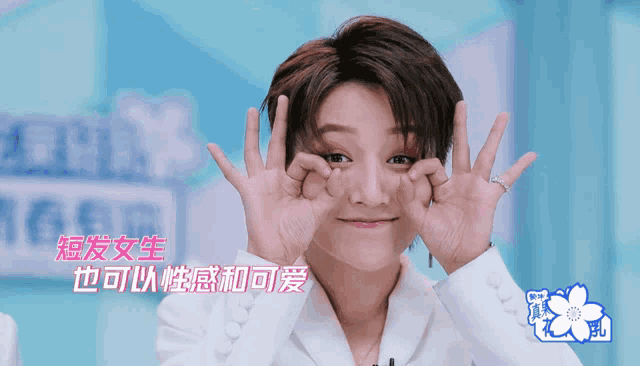 a woman making a face with her hands in front of her face with chinese writing behind her