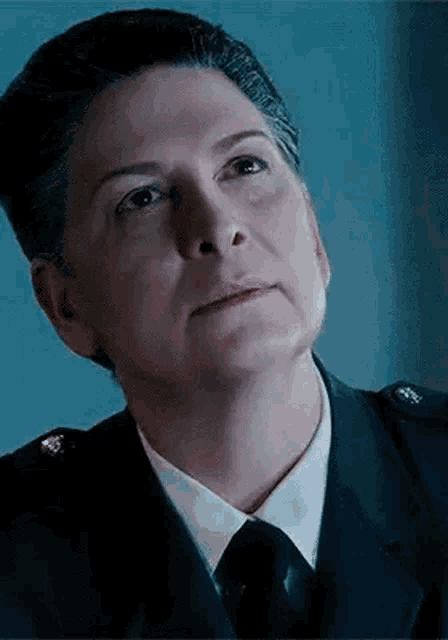 a close up of a woman in a police uniform and tie looking up .