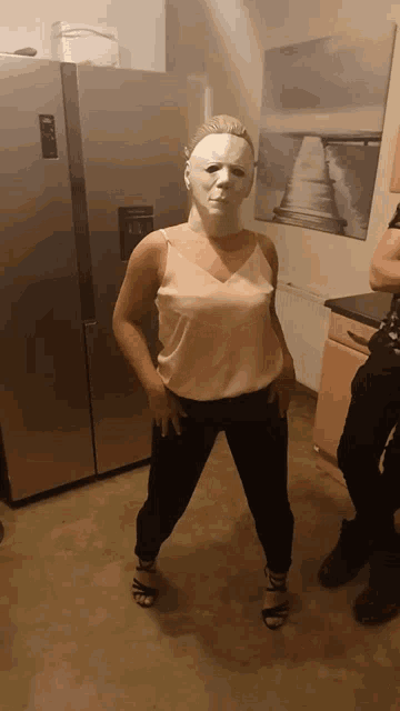 a woman wearing a mask is standing in front of a samsung refrigerator