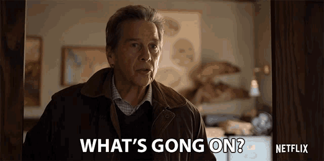 a man in a brown jacket is standing in a doorway and says what 's going on ?