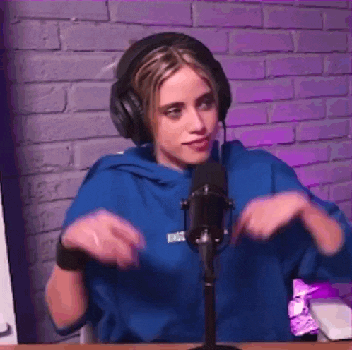 a woman wearing headphones is sitting in front of a microphone in a room .