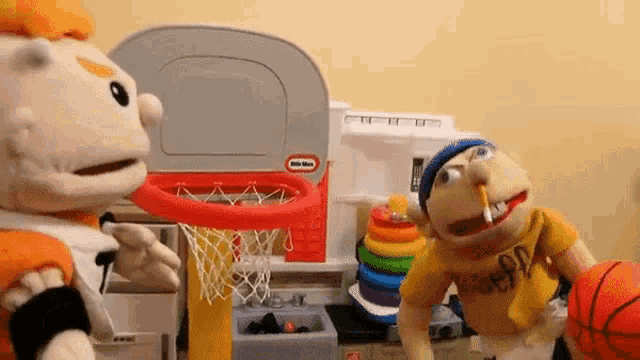 two stuffed animals are playing basketball with a little tikes basketball hoop .