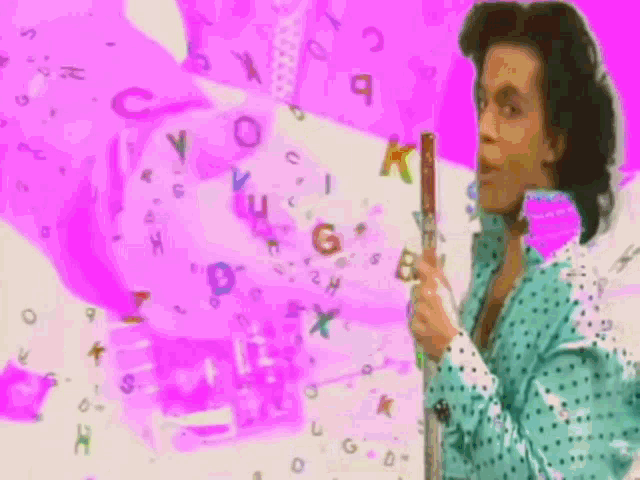 a man in a blue and white polka dot shirt is holding a flute in front of a pink background with letters flying around