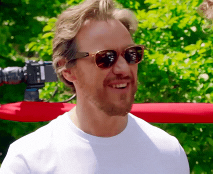 a man wearing sunglasses is smiling in front of a camera
