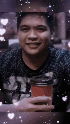 a man is smiling while holding a cup of coffee in his hand .