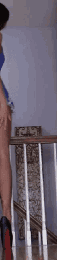 a woman in a blue dress is standing on a set of stairs wearing high heels .
