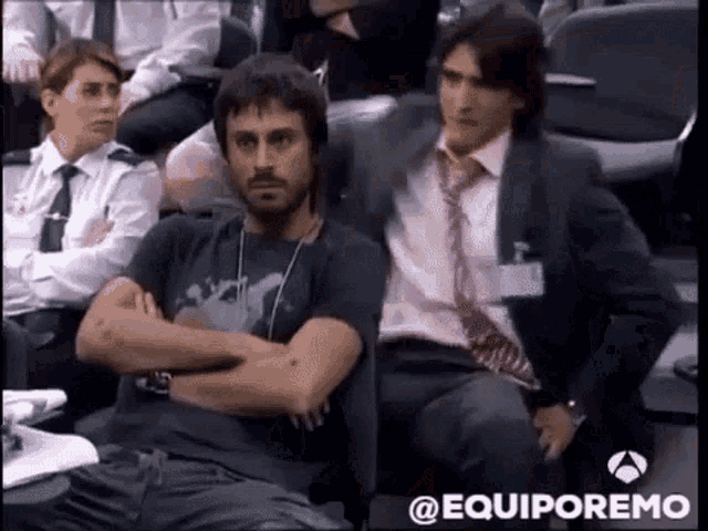 a man in a suit and tie is sitting in a crowd of people .