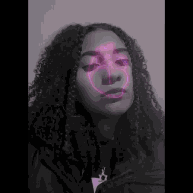 a woman with curly hair has a purple glowing smiley face on her face