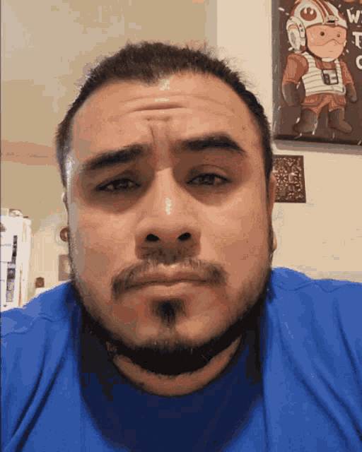 a man with a beard wearing a blue shirt is making a face