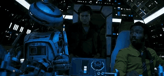 a man is sitting in a chair next to a robot in a room .