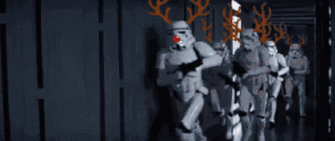 a group of stormtroopers with reindeer antlers on their faces are walking down a hallway .