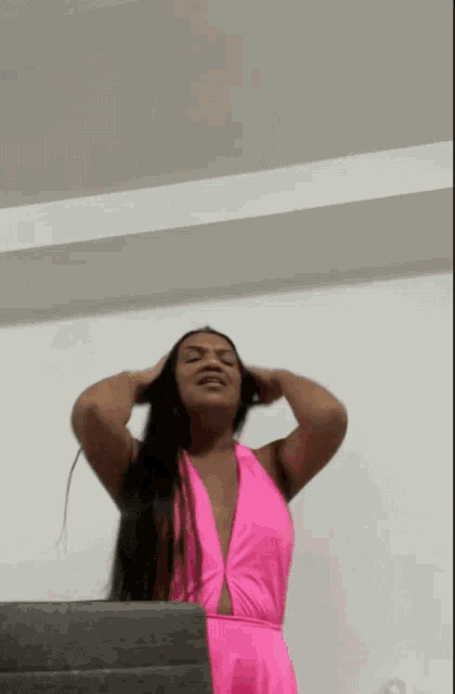 a woman in a pink dress is holding her hair in her hands