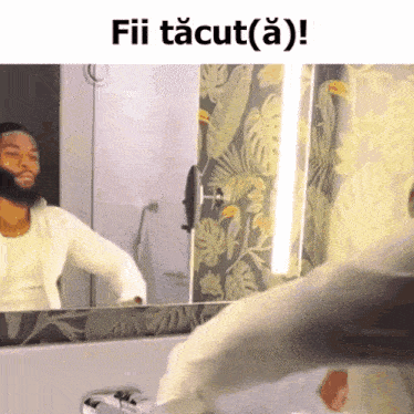 a man in a white shirt is looking at himself in a mirror with the caption fii tacut ( a ) !