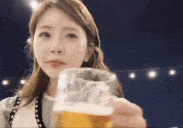 a woman holds a glass of beer in her hand and looks at it
