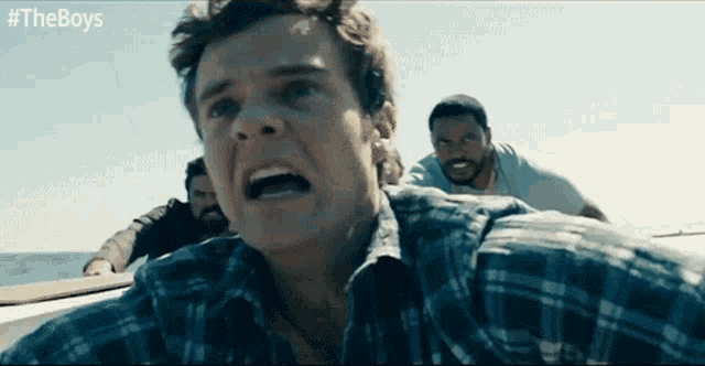 a man in a plaid shirt is screaming while standing on a boat with other men .