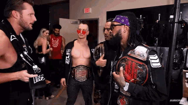 a group of wrestlers are standing in a room with an exit sign
