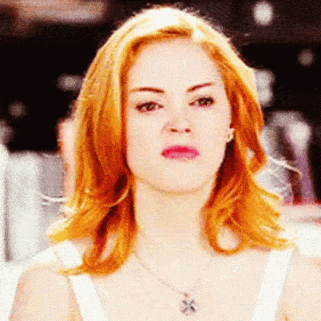 a close up of a woman 's face with red hair and a necklace