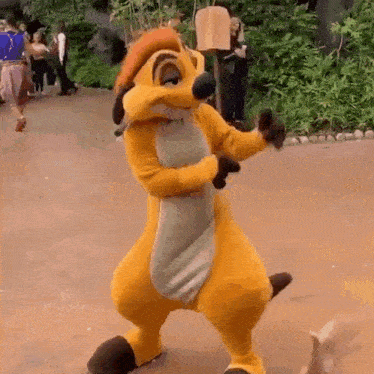 a lion king mascot is dancing in front of a crowd .