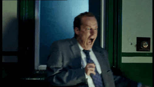 a man in a suit and tie is screaming in front of a door