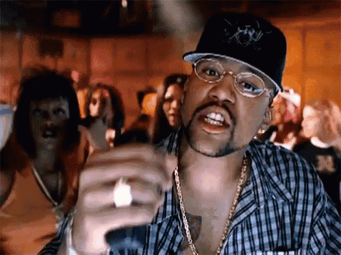 a man wearing a hat and glasses is pointing at the camera