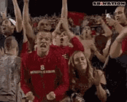 a man in a red shirt with the letter s on it is surrounded by people