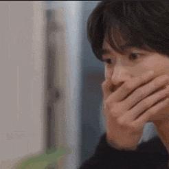 a man is covering his mouth with his hands .