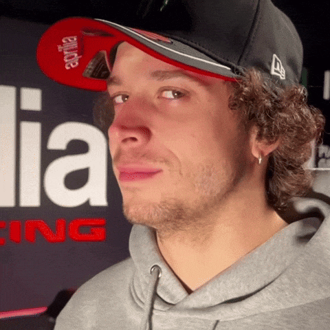 a man wearing a aprilia hat and a grey hoodie