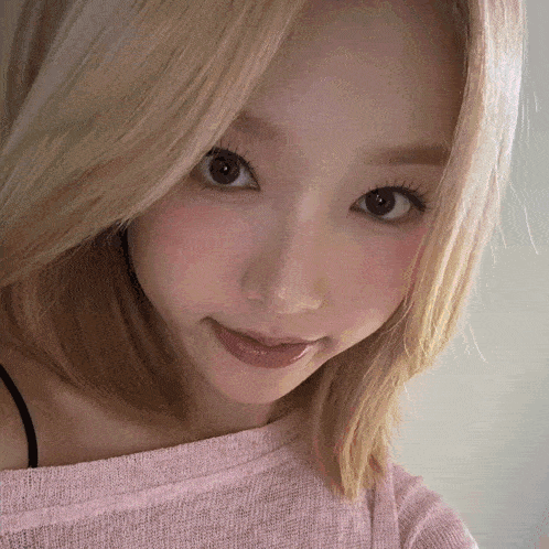 a close up of a woman 's face with a pink sweater on