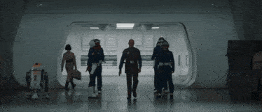 a group of people walking down a hallway with a robot in the foreground that says r2d2