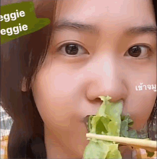 a close up of a woman eating a salad with chopsticks