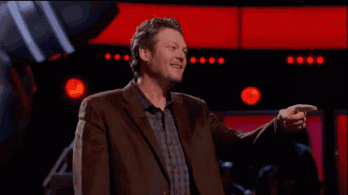 a man in a suit and plaid shirt waves his hand