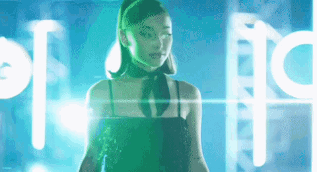 a woman in a black dress and a green headband is standing in front of a green light .