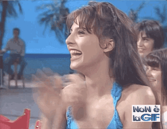 a woman in a blue bikini is laughing with the words non e la gif below her