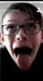 a close up of a person wearing glasses sticking their tongue out .