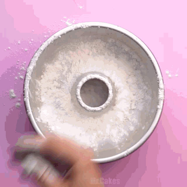 a person is sprinkling powdered sugar on a donut pan