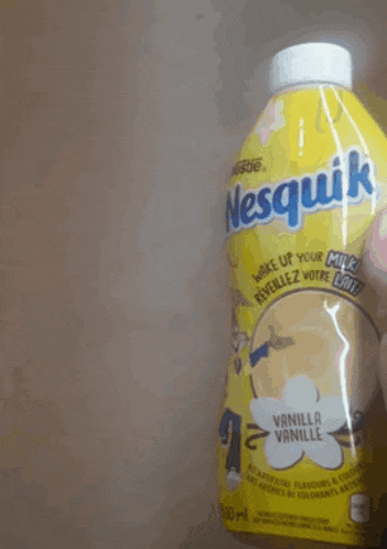a person is holding a yellow bottle of nesquik vanilla milk