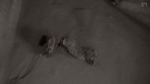 a black and white photo of a person laying on the ground in the snow .