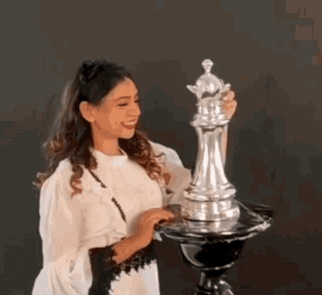 a woman in a white shirt is holding a giant chess piece .