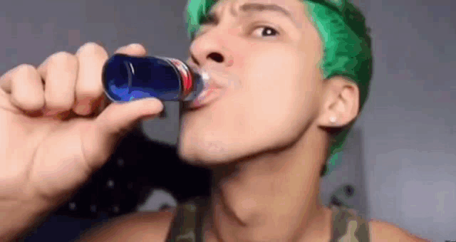 a man with green hair is drinking a can of soda .