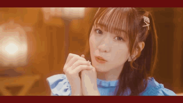 a girl in a blue dress holds her hands together