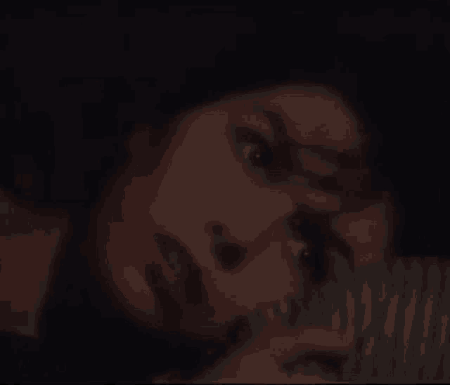 a close up of a woman 's face in a dark room with her eyes closed .
