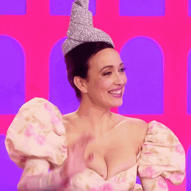 a woman wearing a tiara and a floral dress is smiling and waving