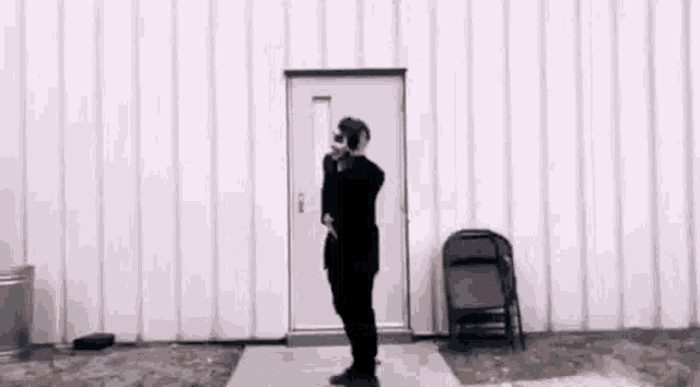 a man in a black suit is standing in front of a white door .